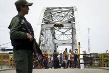People stand next to a closed gate while a Venezuelan soldier stands guard at La Union international bridge, on the border with Colombia at Boca de Grita in Tachira state, Venezuela, August 29, 2015. PHOTO BY REUTERS/Carlos Eduardo Ramirez