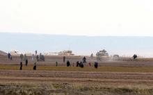 Syrian civilians, with Turkish Army tanks in the background, walk through the Turkish border as they are pictured from a village in Kilis province, Turkey, September 3, 2016. PHOTO BY REUTERS/Ismail Coskun