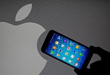 A Samsung Galaxy S5 smartphone is held next to a logo of Apple in this September 23, 2014 illustration photo in Sarajevo. PHOTO BY REUTERS/Dado Ruvic