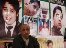 Dr. Farooq Shah, father of Mobin Shah, sits beneath pictures of Hassan Zeb in the rooftop shrine for Hassan Zeb in Peshawar, Pakistan, December 11, 2015. PHOTO BY REUTERS/Caren Firouz