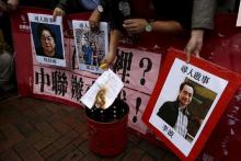 A pro-democracy demonstrator burns a letter next to pictures of missing staff members of a publishing house and a bookstore, during a protest to call for an investigation behind their disappearance, outside the Chinese liaison office in Hong Kong, China, January 3, 2016. PHOTO BY REUTERS/Tyrone Siu