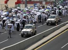 Police vehicles drive past pilgrims on a road in Mina, near the holy city of Mecca, September 24, 2015. PHOTO BY REUTERS/Ahmad Masood