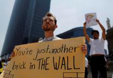 Demonstrators hold placards during a protest against the visit of Donald Trump, at the Angel of Independence monument in Mexico City. PHOTO BY REUTERS/Tomas Bravo
