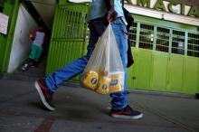 Man carries a plastic bag of basic foods. PHOTO BY REUTERS/Carlos Garcia Rawlins