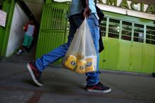 Man carries a plastic bag of basic foods after buying them during a special inspection by Venezuelan soldiers to a municipal market in Caracas, Venezuela, July 15, 2016. PHOTO BY REUTERS/Carlos Garcia Rawlins