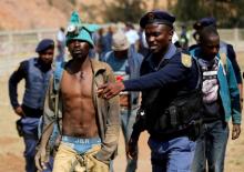 A police officer gestures to a suspected illegal miner after he surfaced from an underground Johannesburg's oldest gold mine in Langlaagte, South Africa, September 12, 2016. PHOTO BY REUTERS/Siphiwe Sibeko