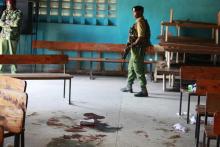 A Kenyan police man walks past blood stains on the floor of a church, after an attack by gunmen on worshippers, at the Coast coastal town of Mombasa