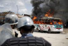 Police stand in front of a burning passenger bus after it was set on fire by unidentified protesters during the nationwide strike, called by the opposition parties against the proposed constitution, in Kathmandu, Nepal, September 20, 2015. PHOTO BY REUTERS/Navesh Chitrakar