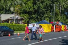 A police officer walks with locals outside the scene of a stabbing attack at a home (L) in Cairns, northern Queensland, December 19, 2014. PHOTO BY REUTERS/Stringer