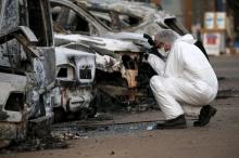 A French police officer photographs burned vehicles outside the Splendid Hotel in Ouagadougou, Burkina Faso, January 17, 2016. PHOTO BY REUTERS/Joe Penney