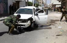 A policeman inspects the remains of a car damaged by a bomb blast in Sanaa