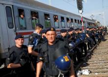 Croatian policemen line up as migrants look on from a train at the Tovarnik railway station, Croatia, September 18, 2015. PHOTO BY REUTERS/Antonio Bronic