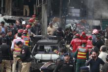 Policemen and residents gather at the site of an explosion outside the police headquarters, in Lahore, February 17, 2015. PHOTO BY REUTERS/Mohsin Raza