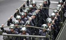 Paramilitary policemen stand on a truck as they travel along a street during an anti-terrorism oath-taking rally in Urumqi, Xinjiang Uighur Autonomous Region