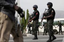 Police officers patrol near a journalist during a protest by the Abuja wing of the "Bring Back Our Girls" group, calling for the release of the Nigerian schoolgirls in Chibok who were kidnapped by Islamist militant group Boko Haram, in Abuja