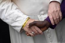 Pope Francis wears a yellow plastic ID bracelet as he shakes hand with a man during a visits at a migrant's reception centre during a pastoral visit in Bologna, Italy, October 1, 2017. PHOTO BY REUTERS/Osservatore Romano