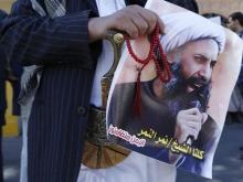 A Shi'ite protester carries a poster of Sheikh Nimr al-Nimr during a demonstration outside the Saudi embassy in Sanaa, October 18, 2014. PHOTO BY REUTERS/Khaled Abdullah