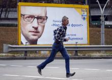 A man runs in front of a pre-election poster with the portrait of Ukrainian Prime Minister Arseny Yatseniuk in Kiev, October 21, 2014. PHOTO BY REUTERS/Gleb Garanich