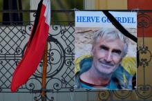 A portrait of mountain guide Frenchman Herve Gourdel hangs near a French flag outside the town hall in Saint-Martin-Vesubie, September 25, 2014. PHOTO BY REUTERS/Patrice Masante