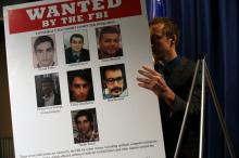 An aide unveils a wanted poster OF Iranian hackers for a coordinated campaign of cyber attacks in 2012 and 2013 on several U.S. banks and a New York dam, at the Justice Department in Washington March 24, 2016. PHOTO BY REUTERS/Jonathan Ernst