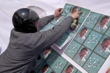 A man puts up an electoral poster of candidate Elyas Hazrati for the upcoming parliamentary elections on a notice board in central Tehran, February 18, 2016. PHOTO BY REUTERS/Raheb Homavandi