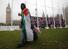 A pro-Palestine supporter wears a Palestinian and Union flag outside the Houses of Parliament in London