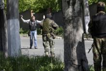 Pro-Russian armed separatists check a journalist at gunpoint in Donetsk