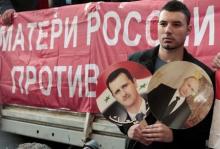 A participant hold images of Russian President Vladimir Putin and Syrian President Bashar al-Assad during an anti-war protest organised by the Communist party near the U.S. embassy in Moscow, September 12, 2013. PHOTO BY REUTERS/Tatyana Makeyeva