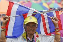 An anti-government protester holds Thai flags as she joins others gathering at their new main stage near the United Nations (U.N.) building, close to the Government House in Bangkok
