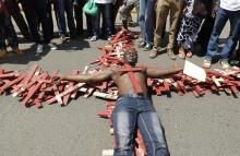 A protester lies on top of wooden crosses, symbolising people killed in a series of attacks, during the #OccupyHarambeeAve protest in Kenya's capital Nairobi, November 25, 2014. PHOTO BY REUTERS/Thomas Mukoya