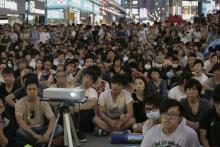 Pro-democracy protesters watch a live broadcast of a meeting between student leaders and government officials on a road blocked by them at Mongkok shopping district in Hong Kong, October 21, 2014. PHOTO BY REUTERS/Bobby Yip