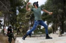 A Palestinian protester throws a stone towards Israeli troops during clashes following a rally marking Nakba Day near Israel's Ofer Prison near the West Bank city of Ramallah, May 15, 2015. PHOTO BY REUTERS/Mohamad Torokman
