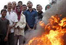 Protesters stand near a burning tyre as they gather to block the highway connecting Nepal to India during a general strike called by Madhesi protesters demonstrating against the new constitution in Birgunj, Nepal, November 5, 2015. PHOTO BY REUTERS/Navesh Chitrakar