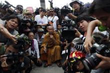 Thai Buddhist monk and protest leader Luang Pu Buddha Issara (C) is surrounded by his supporters and reporters as anti-government protesters wait for police to apologise for firing teargas a day before at a police compound housing a government security group, north of Bangkok
