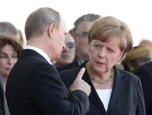 Russian President Vladimir Putin talks with German Chancellor Angela Merkel as they attend the International 70th D-Day Commemoration Ceremony in Ouistreham, June 6, 2014. PHOTO BY REUTERS/Kevin Lamarque