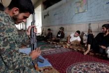 A rebel fighter from Jaysh al-Sunna, operating under a coalition of rebel groups called Jaish al-Fatah, or the army of conquest, prepares his weapon as others rest in Aziziyah village, southern Aleppo countryside, Syria May 17, 2016. PHOTO BY REUTERS/Khalil Ashawi