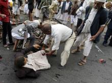Shi'ite Houthi rebels attempt to help a wounded man at the scene of a suicide attack in Sanaa