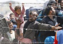 A Syrian refugee reacts as he waits behind border fences to cross into Turkey at Akcakale border gate in Sanliurfa province, Turkey, June 15, 2015. PHOTO BY REUTERS/Umit Bektas