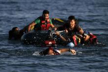 A Syrian refugee swims towards a beach as others are seen on a dinghy whose engine broke down a few hundred meters from the shore of the Greek island of Kos after crossing over from Turkey, August 17, 2015.  PHOTO BY REUTERS/Alkis Konstantinidis