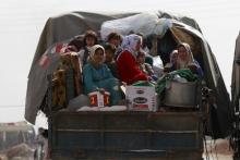 Civilians fleeing the recent fightings in their area sit at the back of a pickup truck with their belongings in the southern countryside of Aleppo, Syria, October 21, 2015. PHOTO BY REUTERS/Hosam Katan