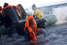 A refugee tries to stand up after falling into the sea as Syrian and Iraqi refugees arrive on a raft on a beach on the Greek island of Lesbos, January 1, 2016. PHOTO BY REUTERS/Giorgos Moutafis