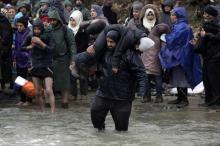 Refugees and migrants cross a river near the Greek-Macedonian border to return to Greece, after an unsuccessful attempt to enter Macedonia, west of the village of Idomeni, Greece, March 15, 2016. PHOTO BY REUTERS/Alexandros Avramidis