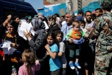 Refugees and migrants holding their registration papers wait to board a bus that will transfer them from a makeshift camp at the port of Piraeus to a newly built relocation centre in the port town of Skaramagkas, in western Athens, Greece, April 18, 2016. PHOTO BY REUTERS/Alkis Konstantinidis