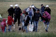 A refugee family carry their belongings during a police operation at a refugee camp at the border between Greece and Macedonia, near the village of Idomeni, Greece, 24 May 2016. PHOTO BY REUTERS/Yannis Kolesidis