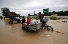 Residents ride on motorcycle taxi to cross a flooded road after heavy rain at Candaba town, Pampanga province, north of Manila, December 17, 2015. PHOTO BY REUTERS/Romeo Ranoco