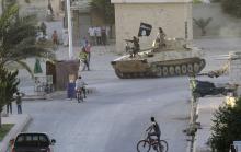 Residents watch militant Islamist fighters taking part in a military parade along the streets of Syria's northern Raqqa province