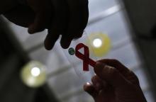 A nurse (L) hands out a red ribbon to a woman, to mark World Aids Day, at the entrance of Emilio Ribas Hospital, in Sao Paulo, December 1, 2014. PHOTO BY REUTERS/Nacho Doce