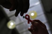 A nurse (L) hands out a red ribbon to a woman, to mark World Aids Day, at the entrance of Emilio Ribas Hospital, in Sao Paulo, December 1, 2014. PHOTO BY REUTERS/Nacho Doce