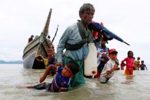 A Rohingya refugee man pulls a child as they walk to the shore after crossing the Bangladesh-Myanmar border by boat through the Bay of Bengal in Shah Porir Dwip, Bangladesh, September 10, 2017. PHOTO BY REUTERS/Danish Siddiqui