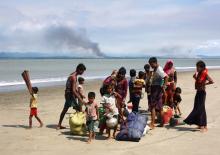 Smoke is seen on Myanmar's side of border as Rohingya refugees collect their belongings on a shore after crossing the Bangladesh-Myanmar border by boat through the Bay of Bengal in Shah Porir Dwip, Bangladesh, September 15, 2017. PHOTO BY REUTERS/Danish Siddiqui